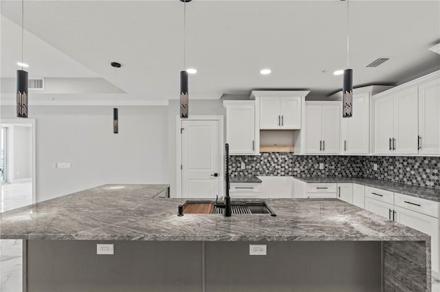 kitchen featuring hanging light fixtures, tasteful backsplash, white cabinets, and a large island