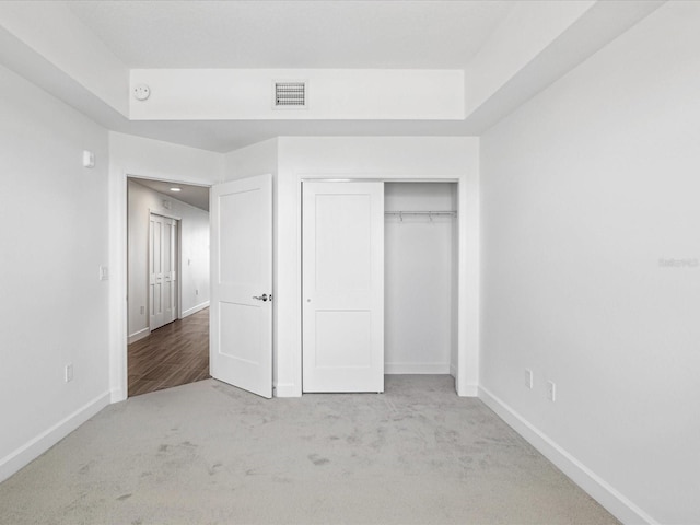 unfurnished bedroom featuring a closet, a raised ceiling, and light hardwood / wood-style flooring