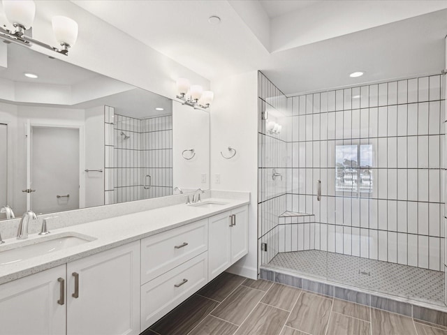 bathroom with double sink vanity and tiled shower