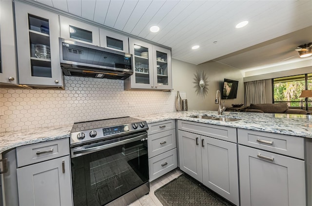 kitchen with sink, gray cabinets, light stone counters, stainless steel appliances, and tasteful backsplash