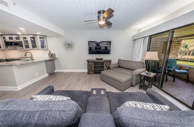 living room featuring wood ceiling, sink, ceiling fan, and light wood-type flooring