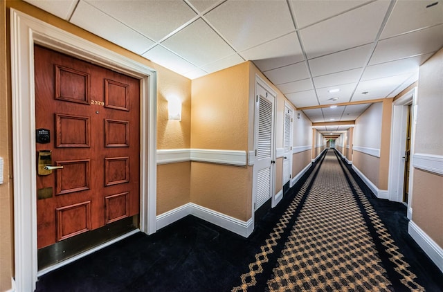 interior space featuring dark carpet and a drop ceiling