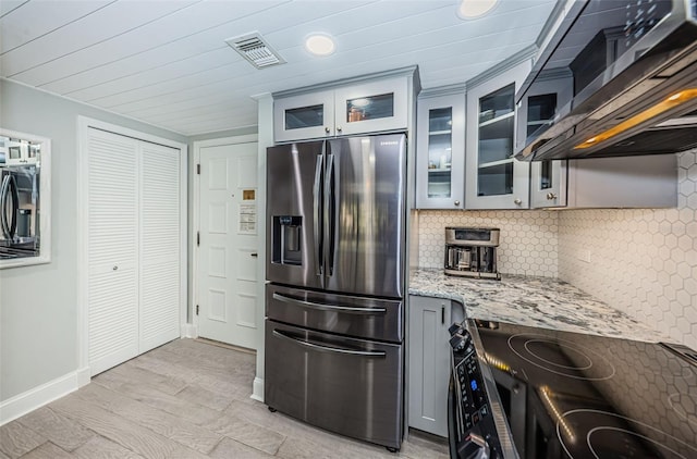 kitchen featuring tasteful backsplash, light hardwood / wood-style flooring, stainless steel refrigerator with ice dispenser, range, and light stone counters