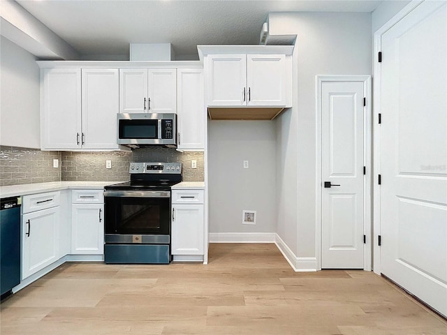 kitchen featuring light wood finished floors, stainless steel appliances, decorative backsplash, light countertops, and white cabinetry