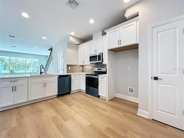 kitchen with visible vents, a sink, white cabinetry, appliances with stainless steel finishes, and decorative backsplash