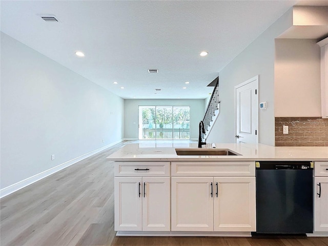 kitchen with baseboards, light wood-style flooring, a sink, decorative backsplash, and dishwasher