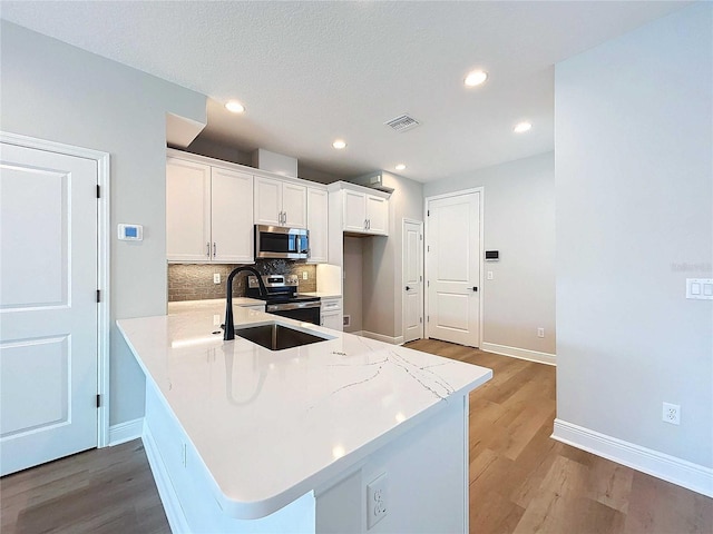 kitchen with visible vents, backsplash, light countertops, stainless steel appliances, and white cabinetry