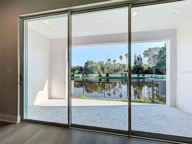 doorway featuring recessed lighting, a water view, a healthy amount of sunlight, and wood finished floors