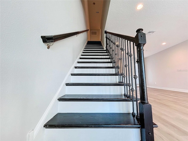 stairs with visible vents, a textured ceiling, wood finished floors, recessed lighting, and baseboards