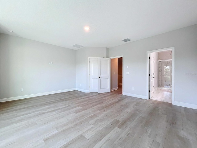 unfurnished bedroom featuring visible vents, light wood-style flooring, ensuite bath, and baseboards