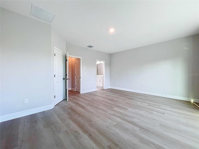 unfurnished room with visible vents, baseboards, and wood finished floors