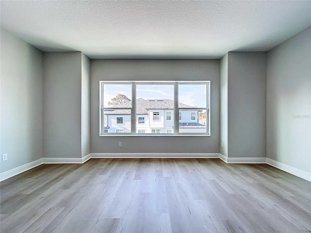 spare room with wood finished floors, baseboards, and a textured ceiling