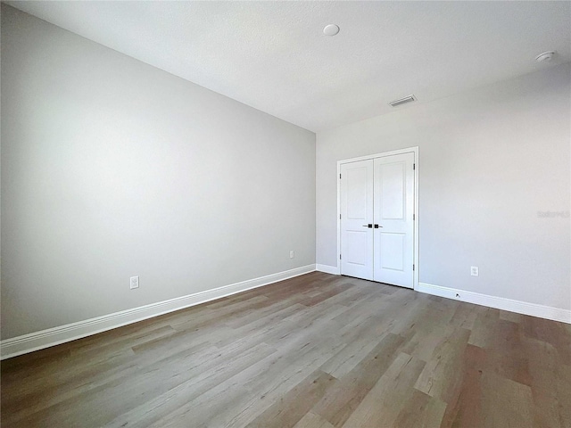 unfurnished room with visible vents, wood finished floors, and baseboards