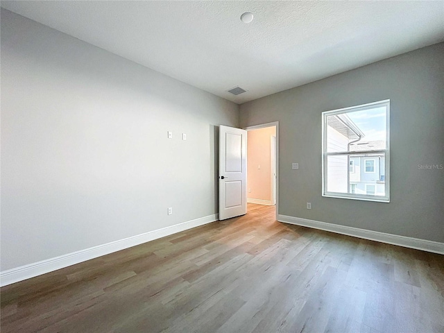 unfurnished bedroom with visible vents, baseboards, a textured ceiling, and wood finished floors