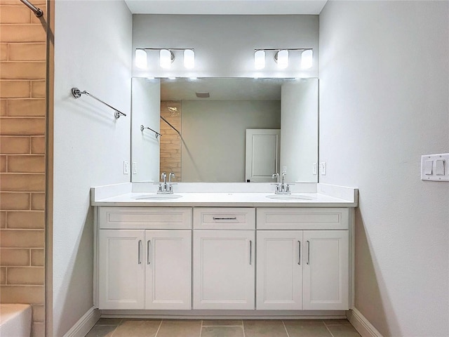 full bathroom featuring double vanity, baseboards, and a sink