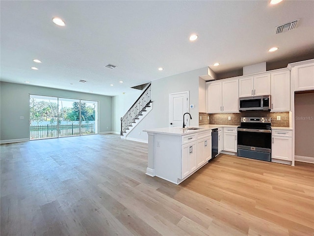 kitchen with visible vents, a peninsula, stainless steel appliances, and open floor plan