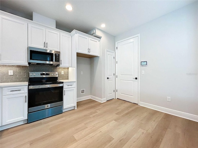 kitchen with tasteful backsplash, baseboards, light wood-style floors, white cabinets, and stainless steel appliances