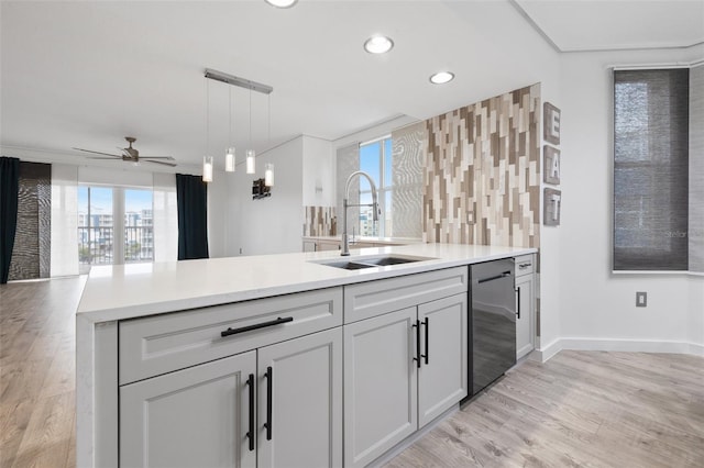 kitchen with dishwasher, sink, decorative backsplash, hanging light fixtures, and light wood-type flooring