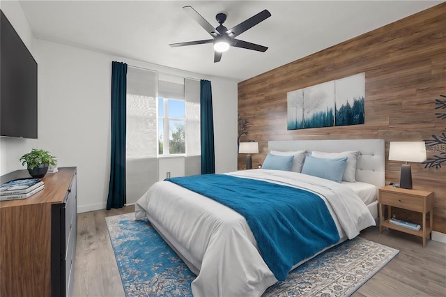 bedroom featuring wooden walls, light hardwood / wood-style floors, and ceiling fan