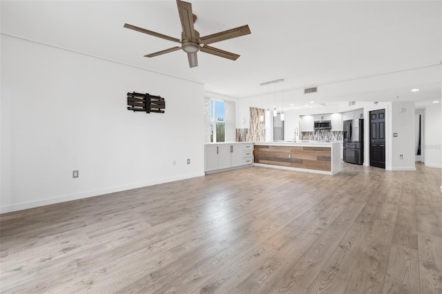 unfurnished living room featuring sink, light hardwood / wood-style flooring, and ceiling fan