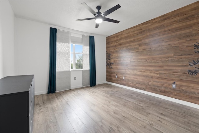 interior space featuring ceiling fan, wooden walls, and light hardwood / wood-style flooring