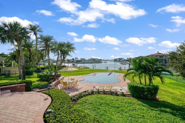 view of pool featuring a patio area, a lawn, and a water view