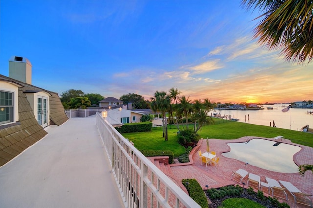 yard at dusk with a patio area and a water view