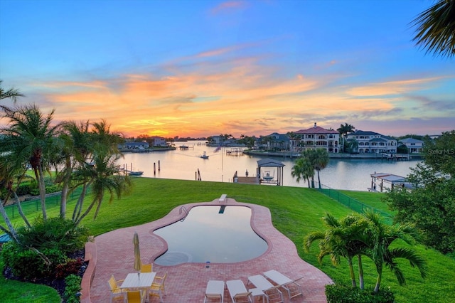 exterior space featuring a patio area, a yard, a boat dock, and a water view