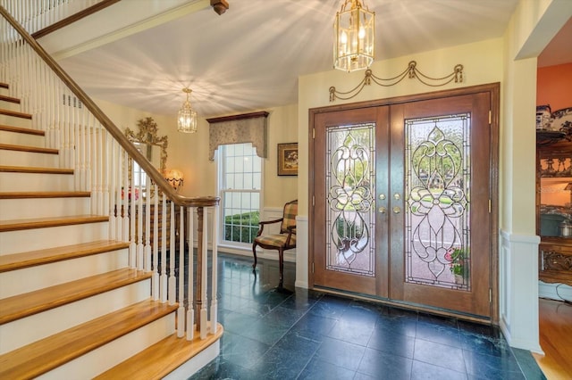 tiled entrance foyer featuring french doors and an inviting chandelier