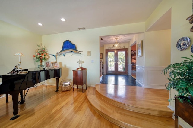 entryway featuring light hardwood / wood-style flooring, french doors, and a chandelier