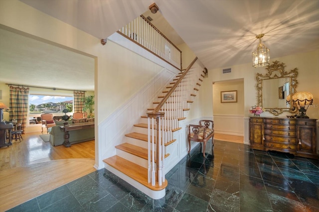 stairs featuring an inviting chandelier and tile flooring