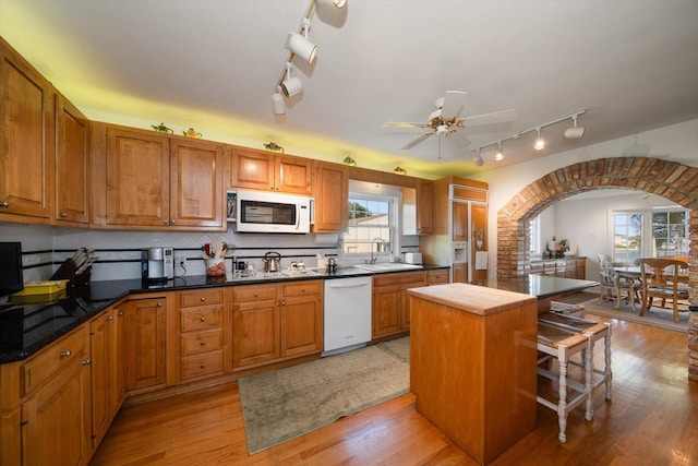 kitchen with white appliances, backsplash, light hardwood / wood-style floors, ceiling fan, and track lighting