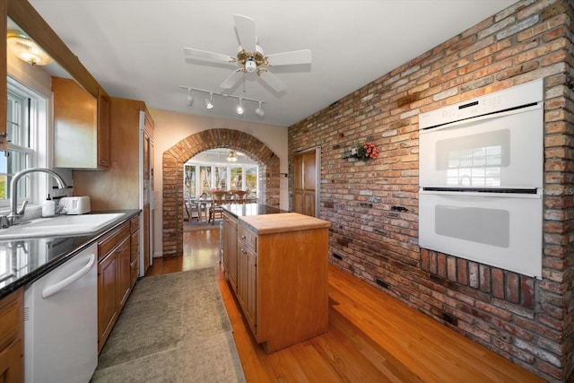 kitchen featuring brick wall, light hardwood / wood-style floors, white appliances, and rail lighting