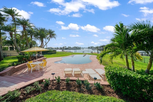 view of swimming pool featuring a patio, a yard, and a water view