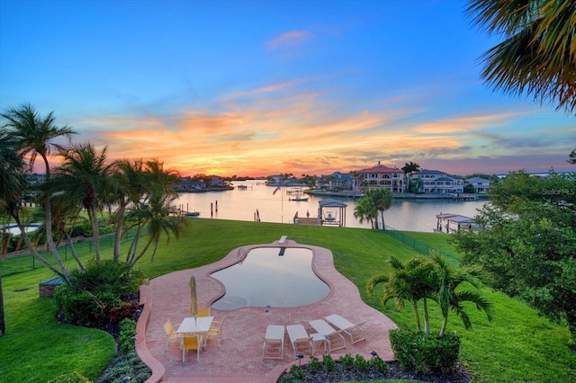 exterior space featuring a patio area, a lawn, a boat dock, and a water view