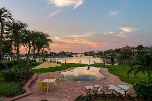 surrounding community with a water view and a lawn