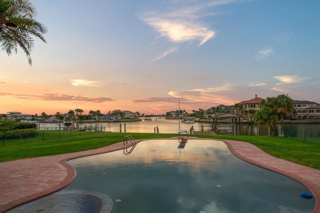 pool at dusk with a water view and a lawn