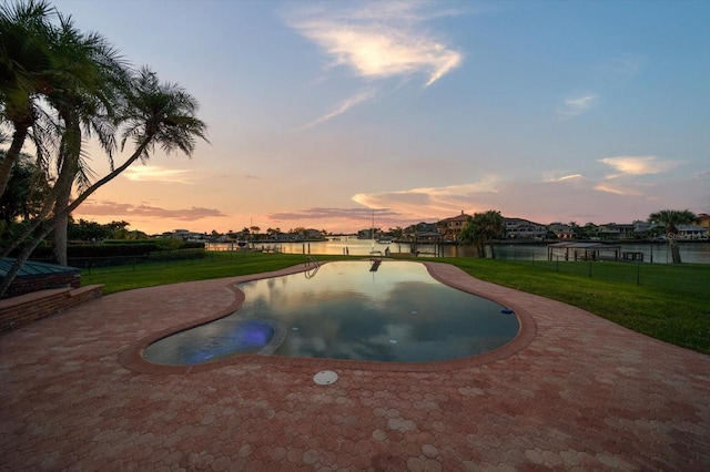 pool at dusk featuring a lawn