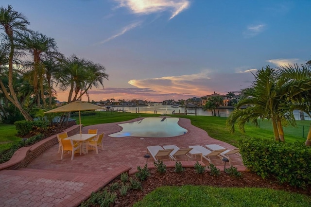 pool at dusk featuring a yard and a patio