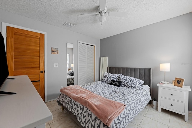 tiled bedroom with ceiling fan, a textured ceiling, and a closet