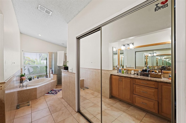 bathroom with tile walls, lofted ceiling, tile patterned flooring, and a textured ceiling