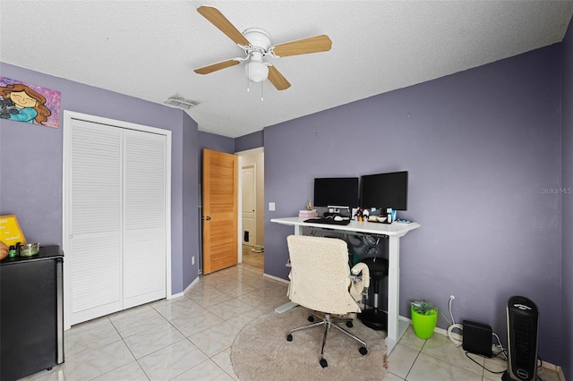 home office featuring ceiling fan, light tile patterned floors, and a textured ceiling