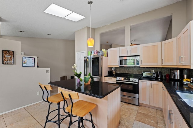 kitchen featuring appliances with stainless steel finishes, tasteful backsplash, decorative light fixtures, a kitchen island, and a breakfast bar area