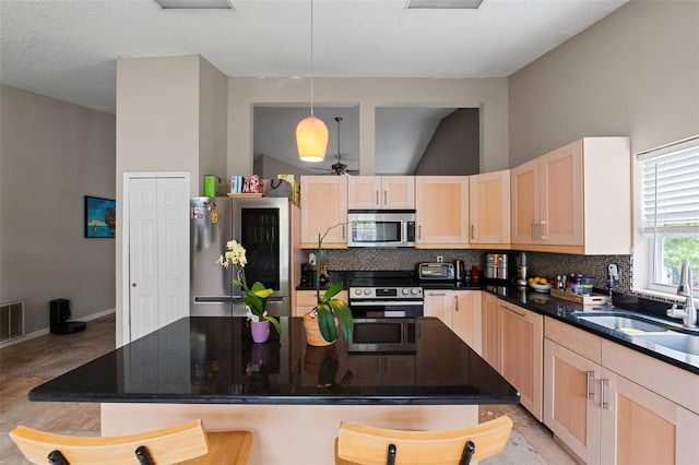 kitchen featuring light brown cabinets, sink, hanging light fixtures, decorative backsplash, and appliances with stainless steel finishes