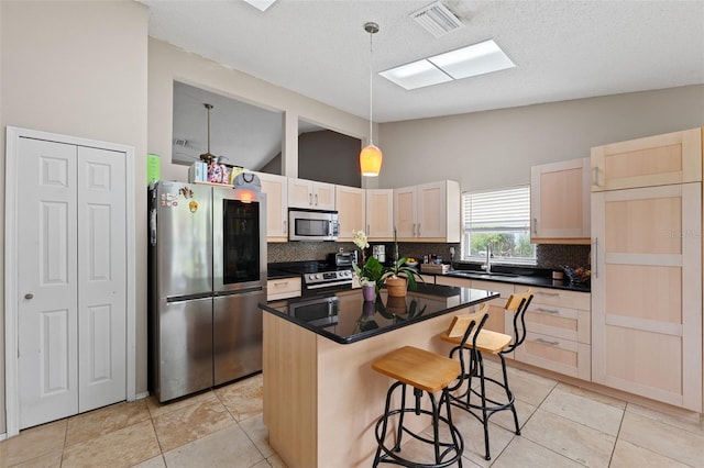 kitchen with backsplash, stainless steel appliances, sink, light brown cabinets, and a kitchen island