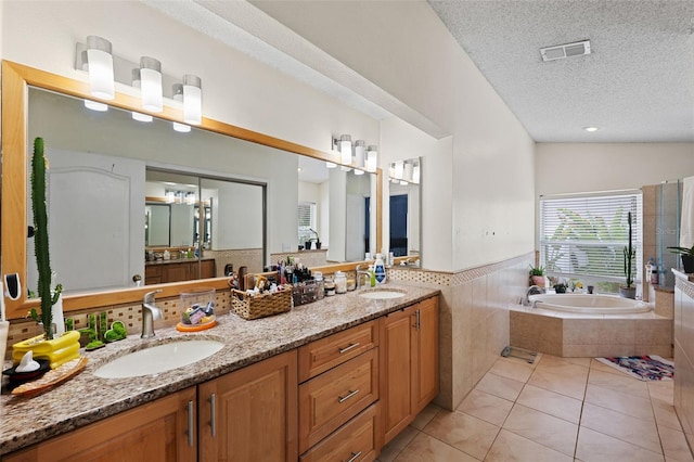 bathroom with vanity, a textured ceiling, a relaxing tiled tub, tile patterned flooring, and lofted ceiling