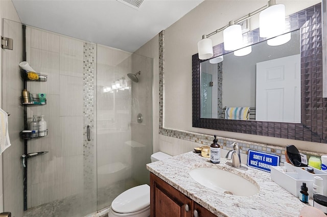 bathroom featuring decorative backsplash, vanity, a shower with shower door, and toilet