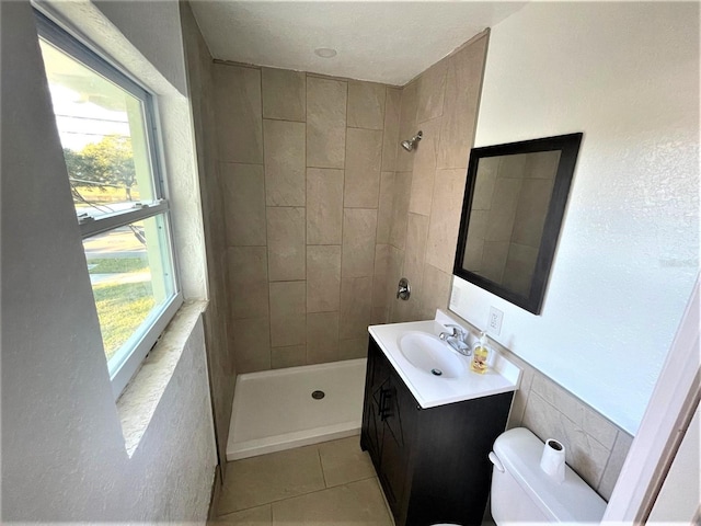 bathroom with toilet, tile flooring, large vanity, and tiled shower