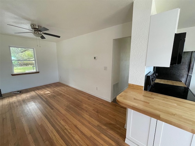 kitchen with ceiling fan, wooden counters, wood-type flooring, white cabinetry, and range