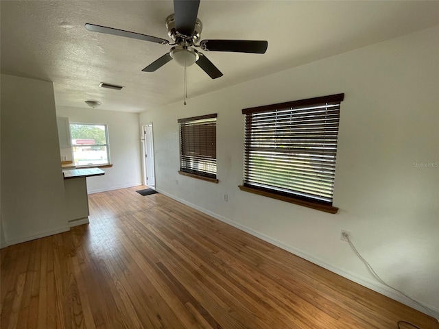 unfurnished room with a textured ceiling, wood-type flooring, and ceiling fan